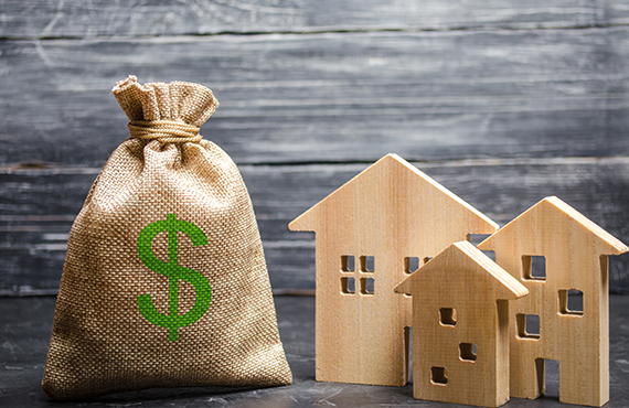 Image of a burlap sack with a dollar sign on it next to three small wooden cutouts of houses